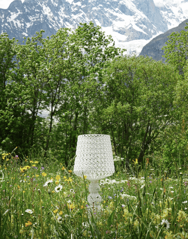 A meadow scene featuring a Mini Kabuki Table Lamp by Kartell in Transparent Crystal